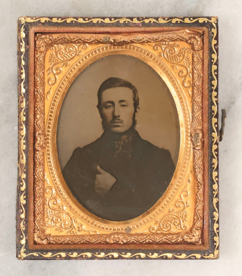 Lot 100 - Antique 1/9th Plate Ambrotype Photograph Of Young Man With Mustache And Checkered Scarf, With Hand Tucked In Shirt Buttons, In Half Leatherette Case With Urn Motif
