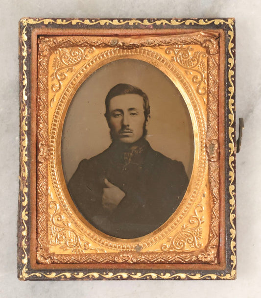 Lot 100 - Antique 1/9th Plate Ambrotype Photograph Of Young Man With Mustache And Checkered Scarf, With Hand Tucked In Shirt Buttons, In Half Leatherette Case With Urn Motif