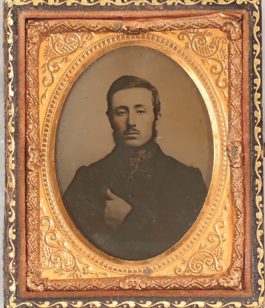 Lot 100 - Antique 1/9th Plate Ambrotype Photograph Of Young Man With Mustache And Checkered Scarf, With Hand Tucked In Shirt Buttons, In Half Leatherette Case With Urn Motif