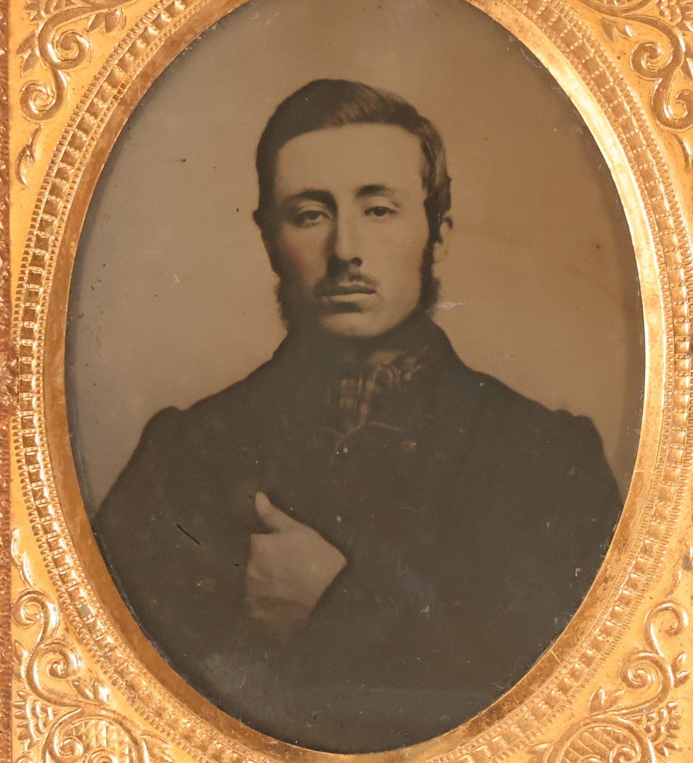 Lot 100 - Antique 1/9th Plate Ambrotype Photograph Of Young Man With Mustache And Checkered Scarf, With Hand Tucked In Shirt Buttons, In Half Leatherette Case With Urn Motif