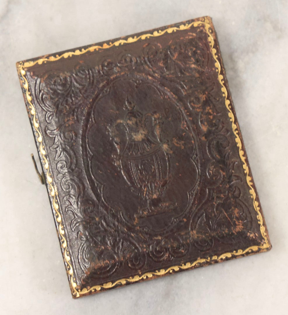 Lot 100 - Antique 1/9th Plate Ambrotype Photograph Of Young Man With Mustache And Checkered Scarf, With Hand Tucked In Shirt Buttons, In Half Leatherette Case With Urn Motif
