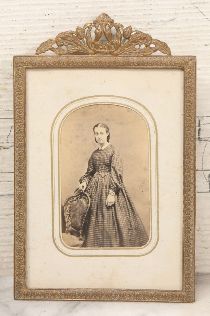 Lot 105 - Antique Carte De Visite C.D.V.. Photograph Of Teenage Girl In Checkered Dress In Brass Tin Frame With Floral Crest And Hanging Loop, 4-3/8" x 6-7/8"