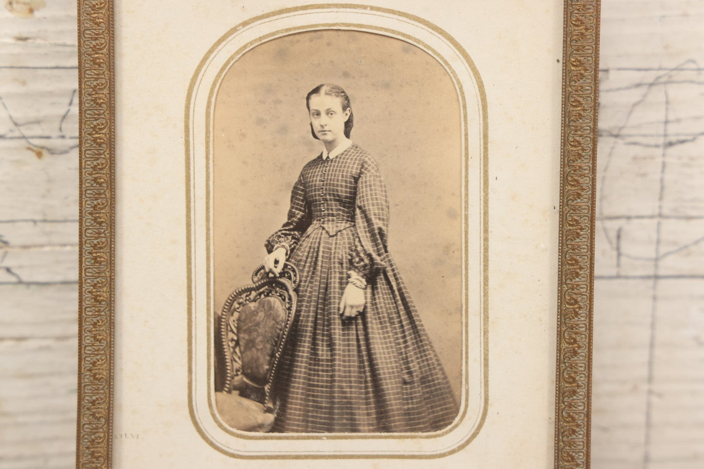 Lot 105 - Antique Carte De Visite C.D.V.. Photograph Of Teenage Girl In Checkered Dress In Brass Tin Frame With Floral Crest And Hanging Loop, 4-3/8" x 6-7/8"