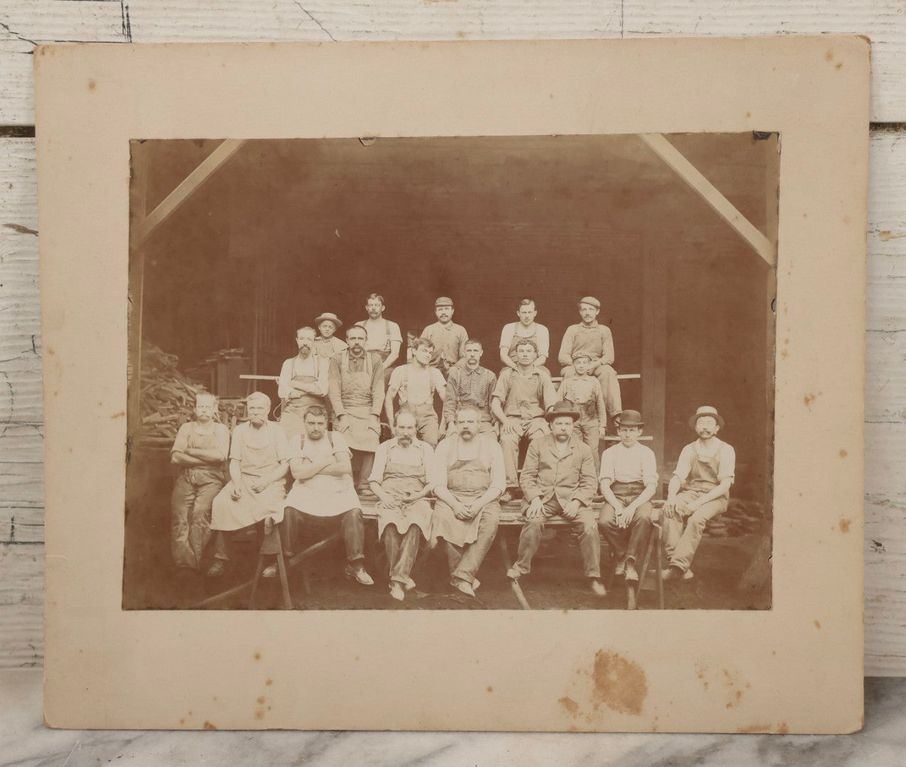 Lot 109 - Antique Boarded Occupational Photograph Of Lumberyard Workers In Work Clothes Posed Atop Stacked Lumber On Sawhorses Before Piles Of Wood
