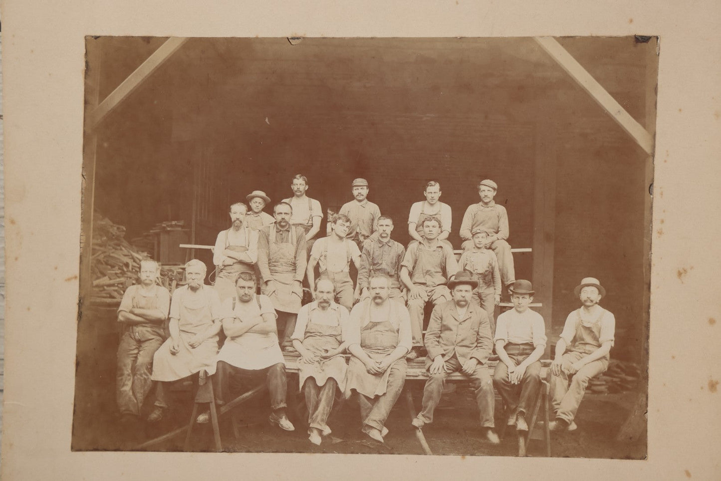 Lot 109 - Antique Boarded Occupational Photograph Of Lumberyard Workers In Work Clothes Posed Atop Stacked Lumber On Sawhorses Before Piles Of Wood