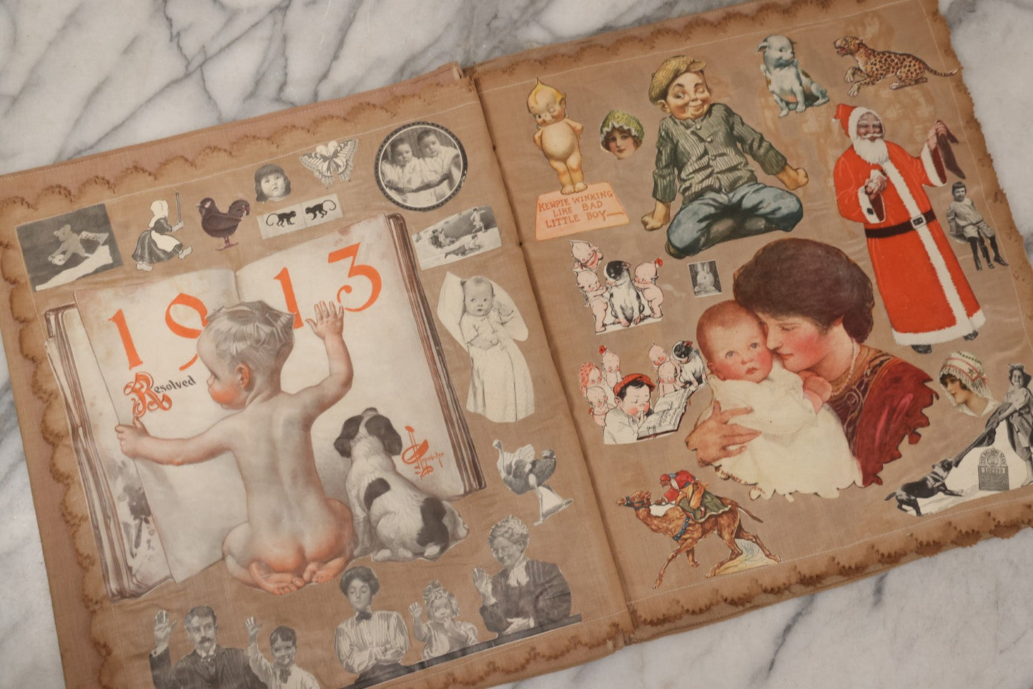 Lot 134 - Antique Linen Scrapbook With Fabric Pages Containing Over 100 Hand Cut Magazine Clippings Including Santa, Children, Animals, Kewpies, Women, Advertisements, And More Circa 1913