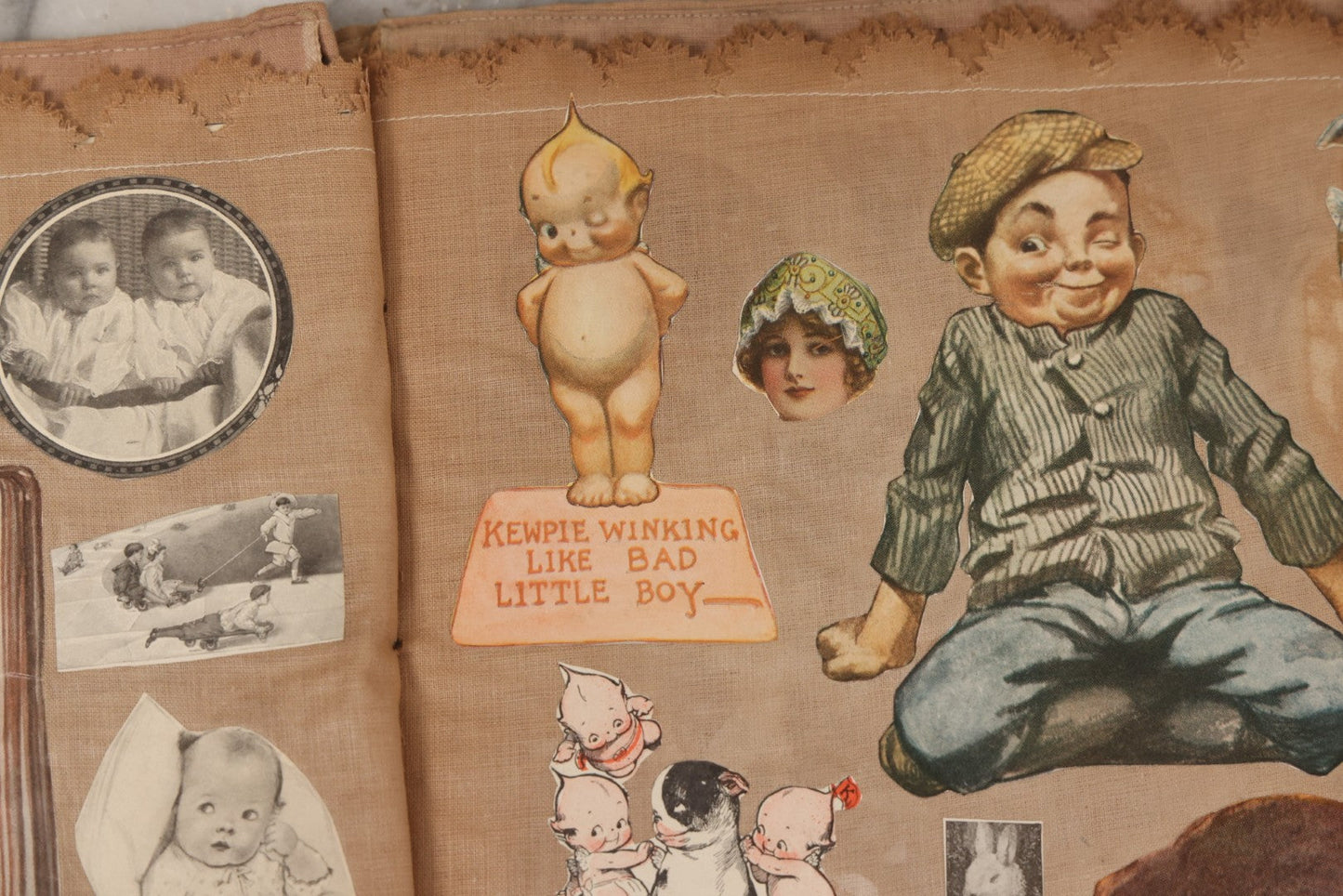 Lot 134 - Antique Linen Scrapbook With Fabric Pages Containing Over 100 Hand Cut Magazine Clippings Including Santa, Children, Animals, Kewpies, Women, Advertisements, And More Circa 1913