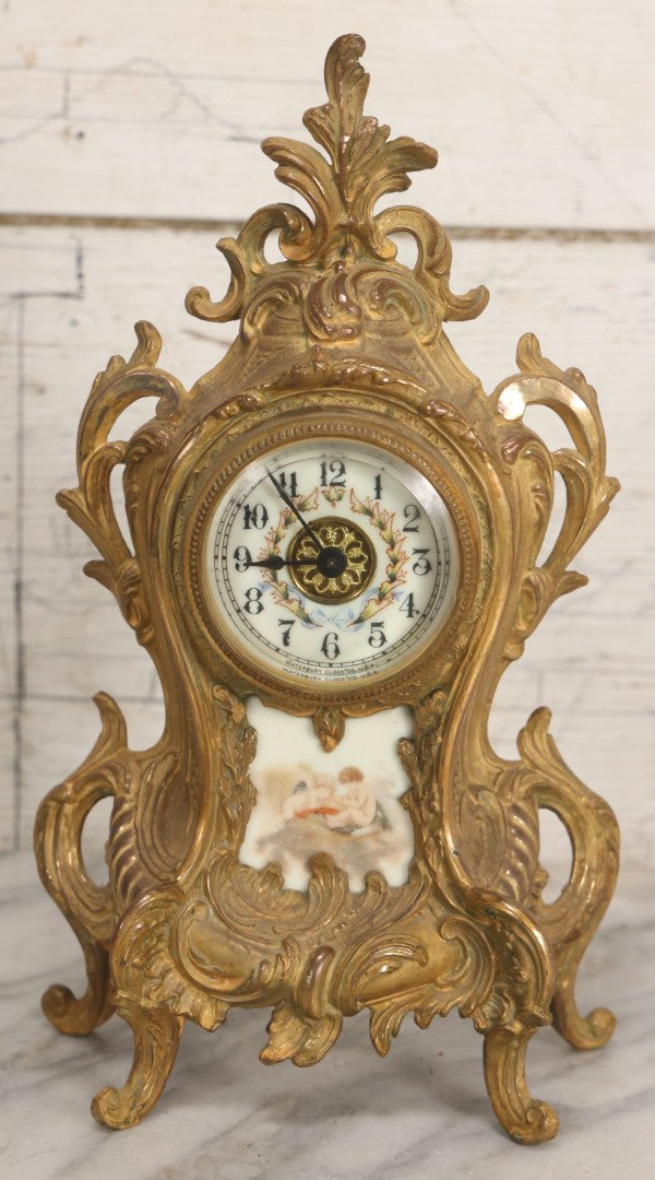 Lot 012 - Antique Waterbury Clock Co. Gold-Painted Spelter Mantel Clock With Hand-Painted Dial And Cupid Scene Panel, Circa 1890s Working Condition, 11" H