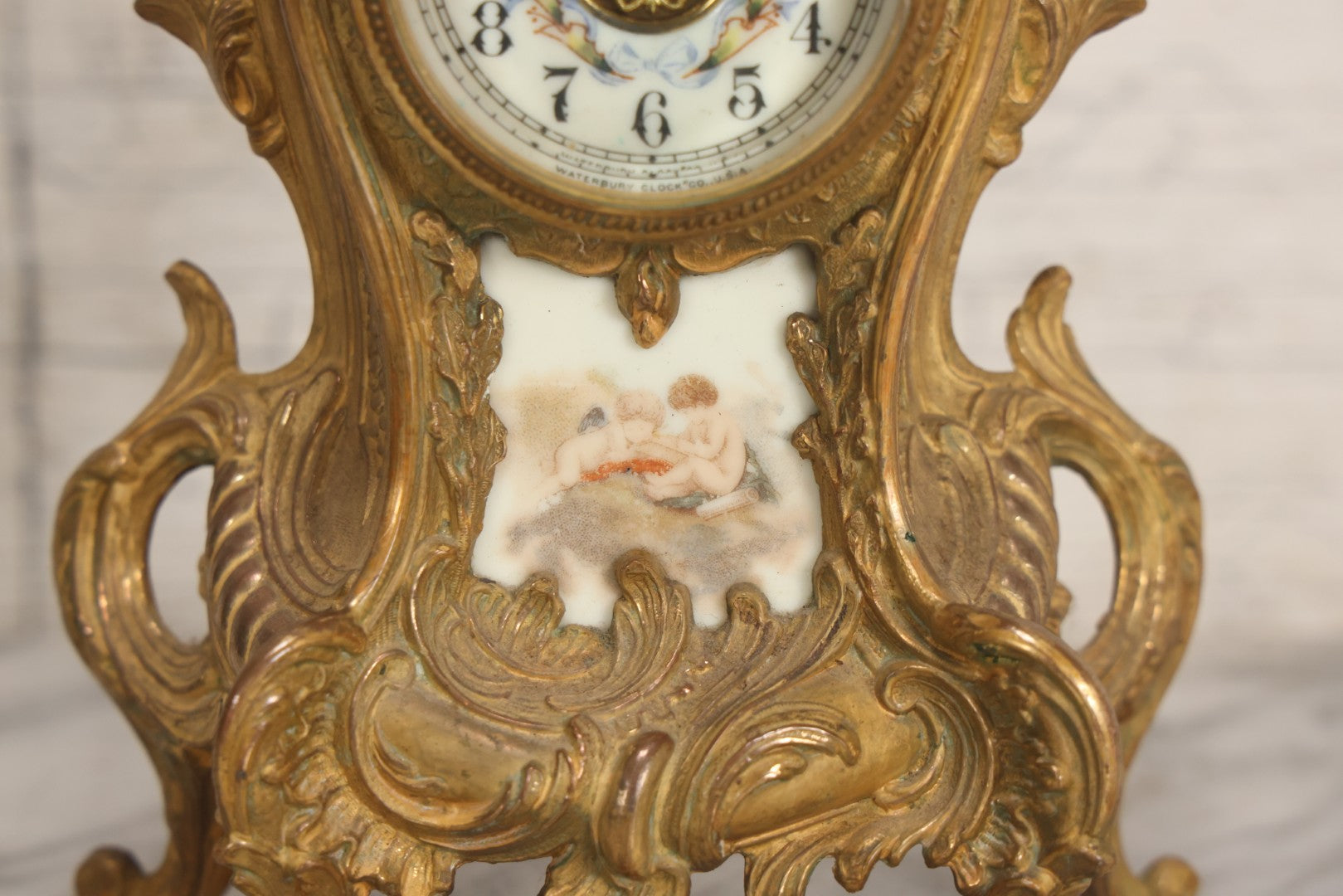 Lot 012 - Antique Waterbury Clock Co. Gold-Painted Spelter Mantel Clock With Hand-Painted Dial And Cupid Scene Panel, Circa 1890s Working Condition, 11" H