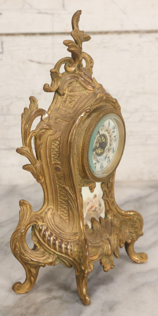 Lot 012 - Antique Waterbury Clock Co. Gold-Painted Spelter Mantel Clock With Hand-Painted Dial And Cupid Scene Panel, Circa 1890s Working Condition, 11" H