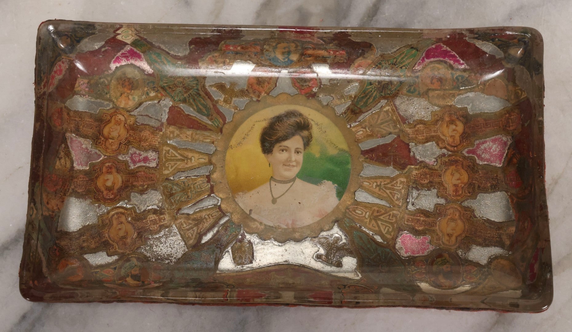 Lot 031 - Antique Reverse Painted And Collaged Cigar Bands Glass Tray With Portrait Of Woman And Red Felt Backing, 8-7/8" x 5"