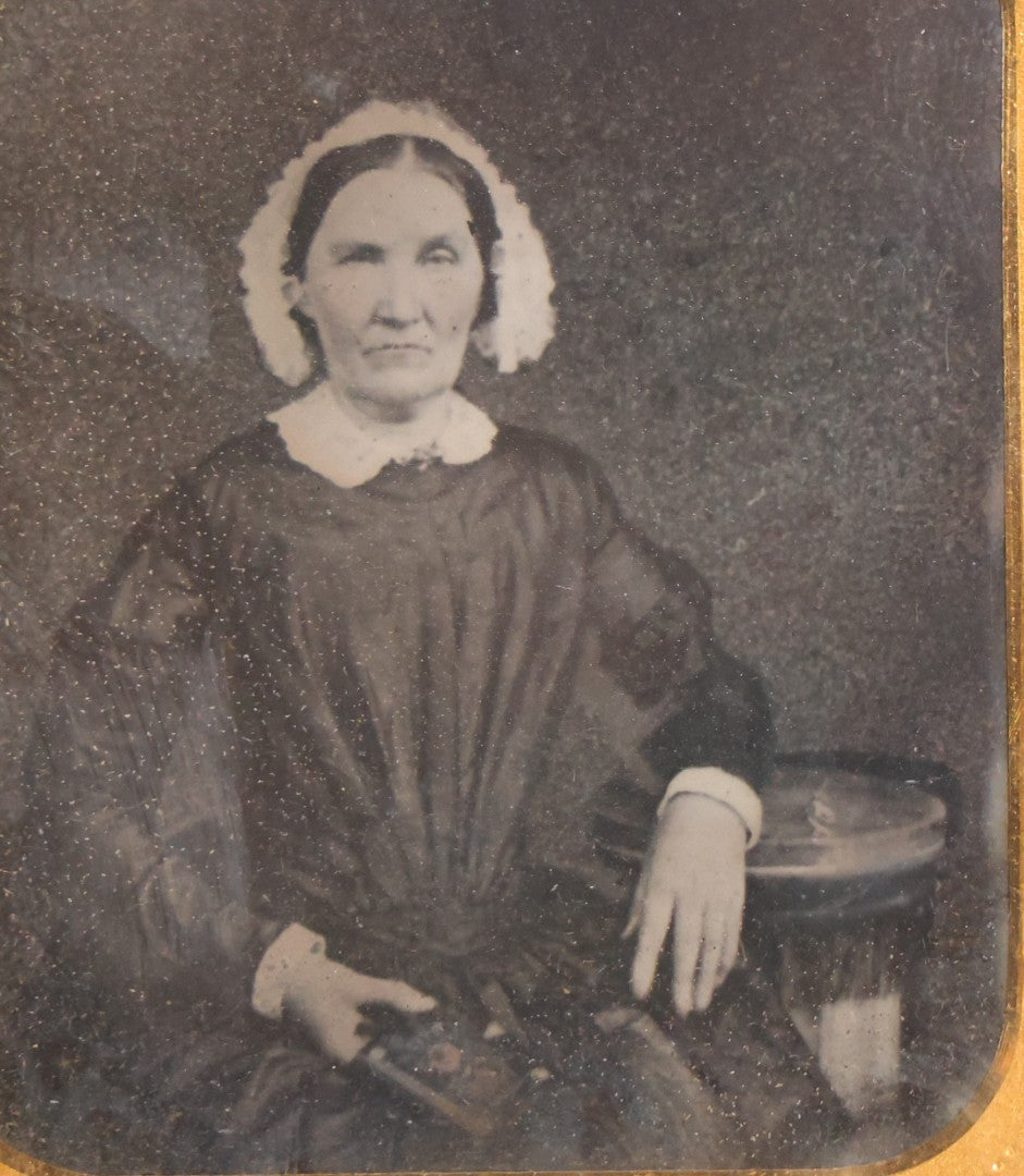 Lot 047 - Antique 1/6th Plate Ruby Ambrotype Photograph Of Elderly Woman In White Bonnet Holding Object, Possibly A Book, In Full Split Leatherette Union Case