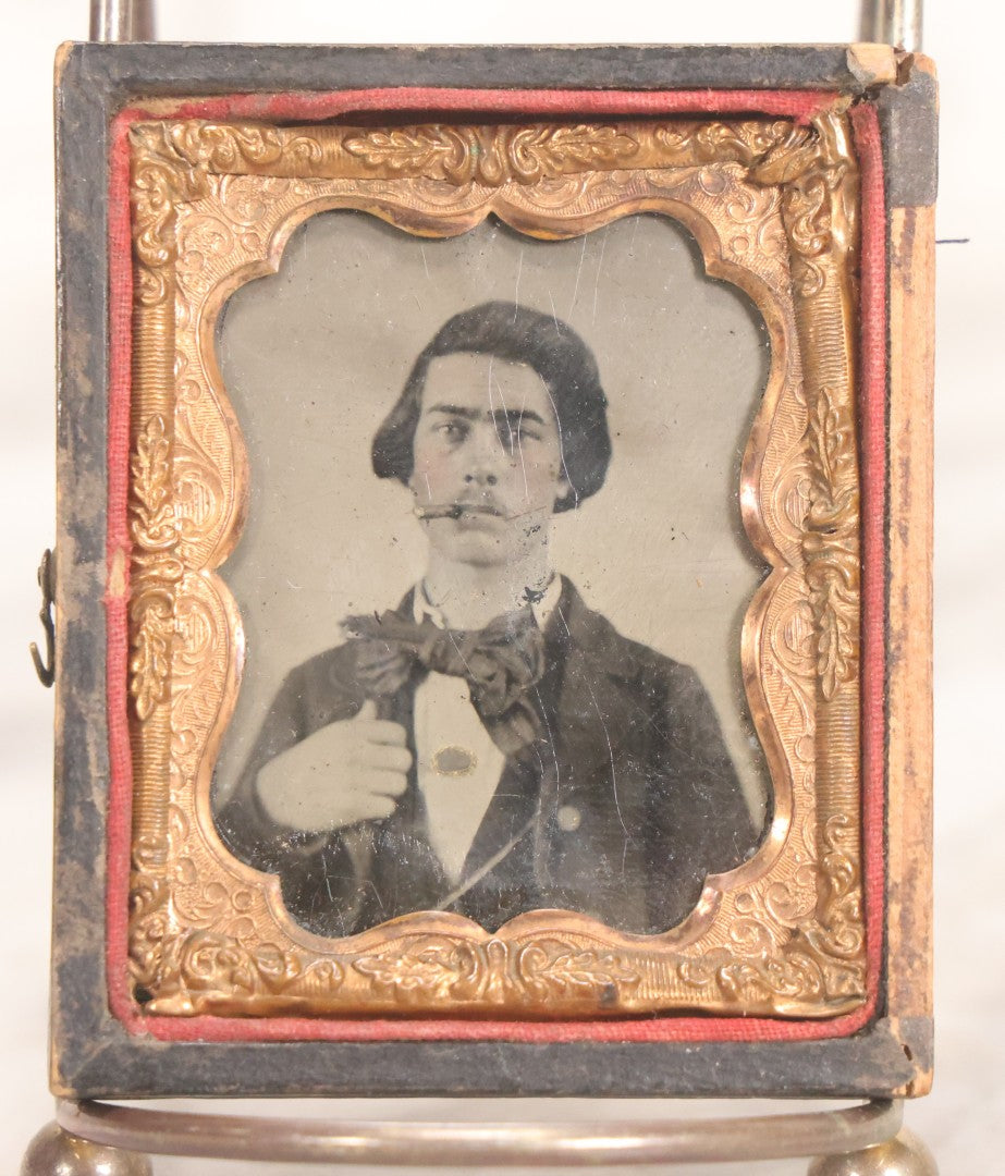 Lot 060 - Antique 1/9th Plate Tintype Photograph Of Young Man With Long Dark Hair And Giant Bowtie Smoking A Cigar, In Full Split Leatherette Union Case