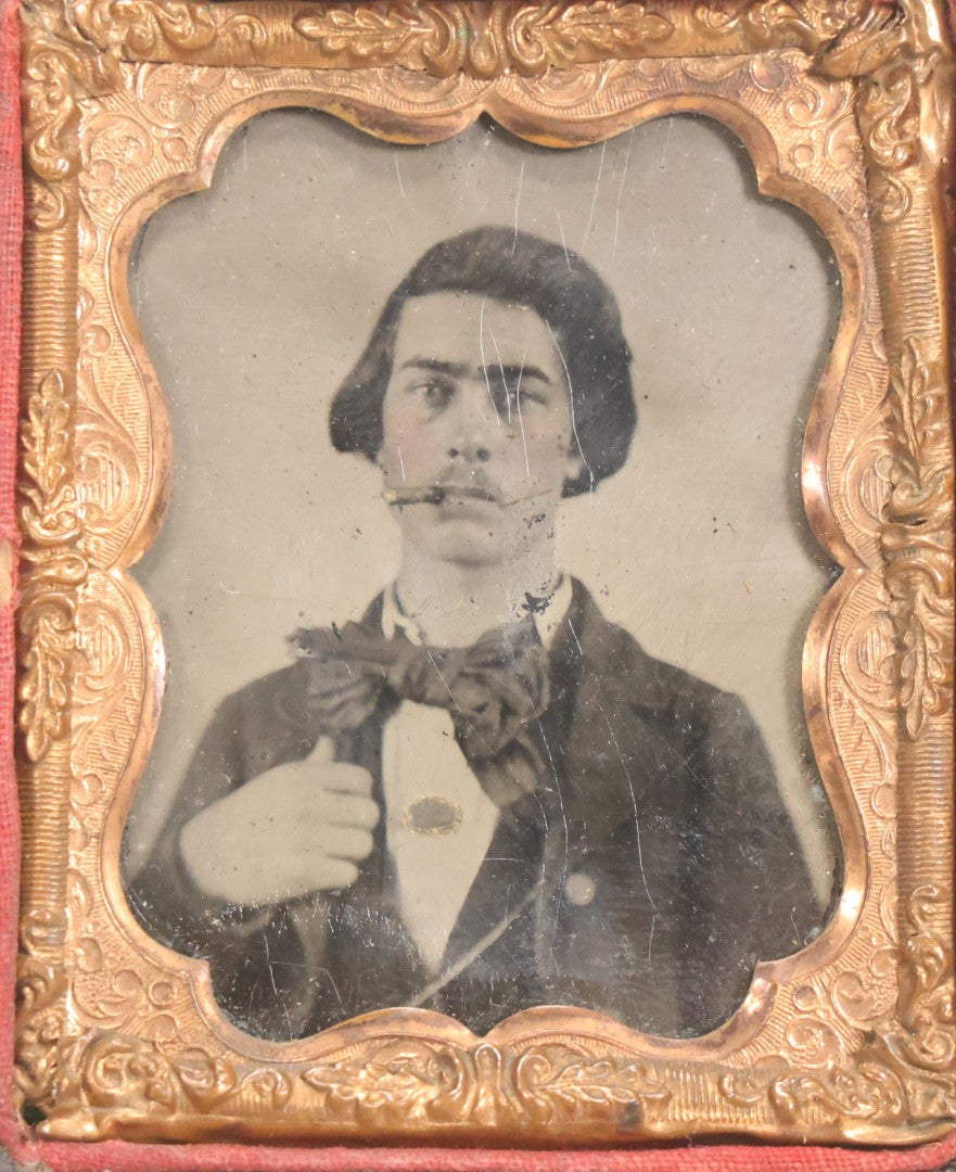 Lot 060 - Antique 1/9th Plate Tintype Photograph Of Young Man With Long Dark Hair And Giant Bowtie Smoking A Cigar, In Full Split Leatherette Union Case