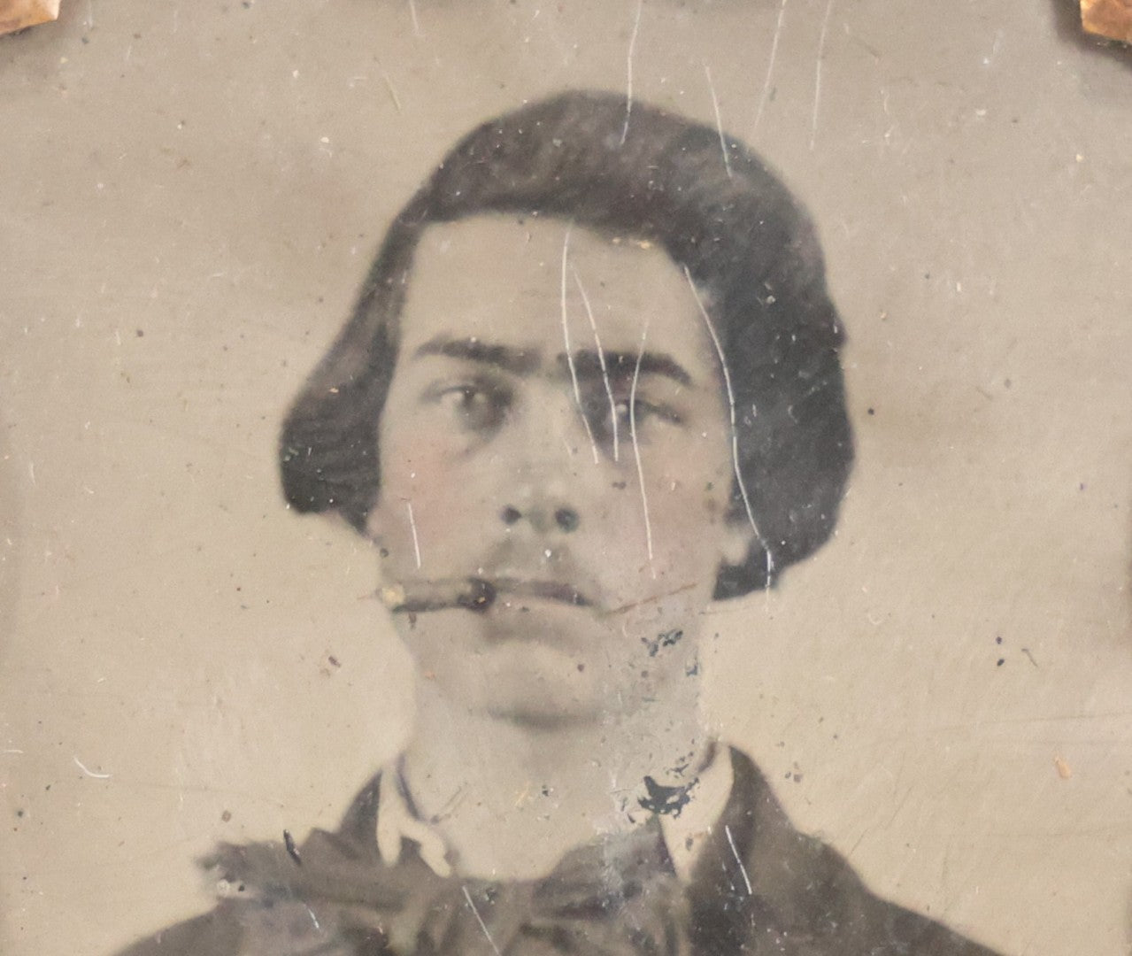 Lot 060 - Antique 1/9th Plate Tintype Photograph Of Young Man With Long Dark Hair And Giant Bowtie Smoking A Cigar, In Full Split Leatherette Union Case