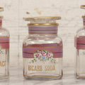 Lot 051 - Antique Three-Piece Painted Glass Bathroom Apothecary Jar Set For Listerine, Bicarb Soda, And Ponds Extract With Gold Lettering, Decorative Lines, And Matching Rose-Decorated Stoppers