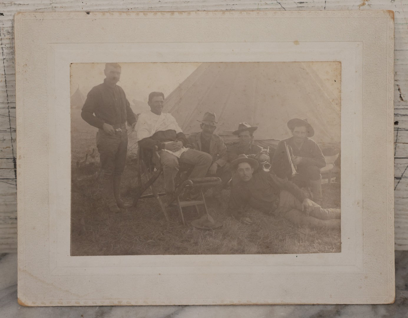 Lot 145 - Antique Boarded Photograph Of Soldiers Relaxing At Camp, Including Buglers And A Man Being Shaved, Posed Before Large Canvas Tent