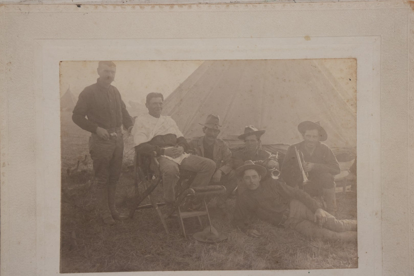 Lot 145 - Antique Boarded Photograph Of Soldiers Relaxing At Camp, Including Buglers And A Man Being Shaved, Posed Before Large Canvas Tent