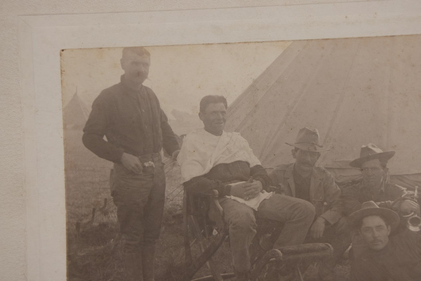 Lot 145 - Antique Boarded Photograph Of Soldiers Relaxing At Camp, Including Buglers And A Man Being Shaved, Posed Before Large Canvas Tent