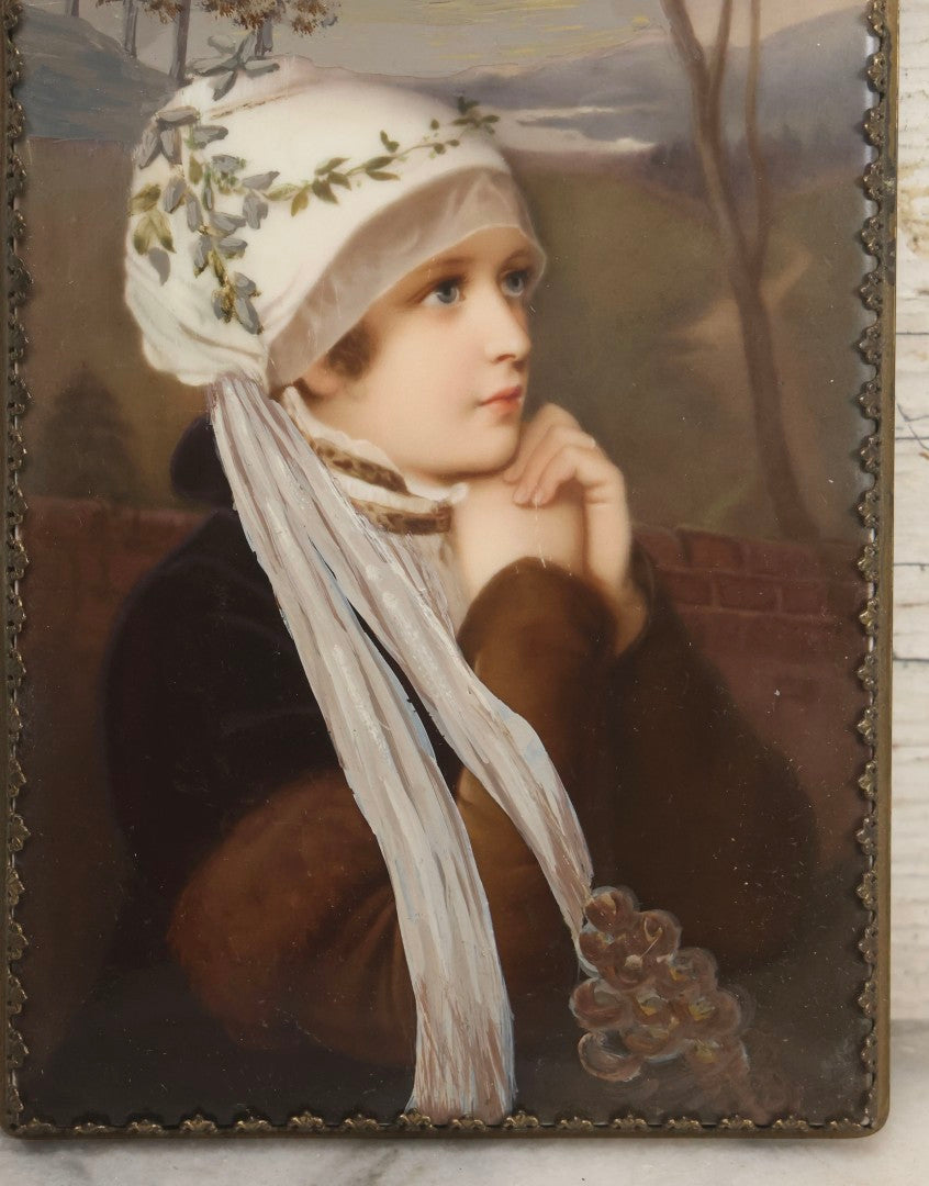 Lot 012 - Antique Painted Porcelain Tile Of Young Praying Woman In Brass Frame With Crest, Note Large Diagonal Crack Through Tile And Multiple Cracks From Upper Left Corner Damage, 4-7/8" x 9-1/8"