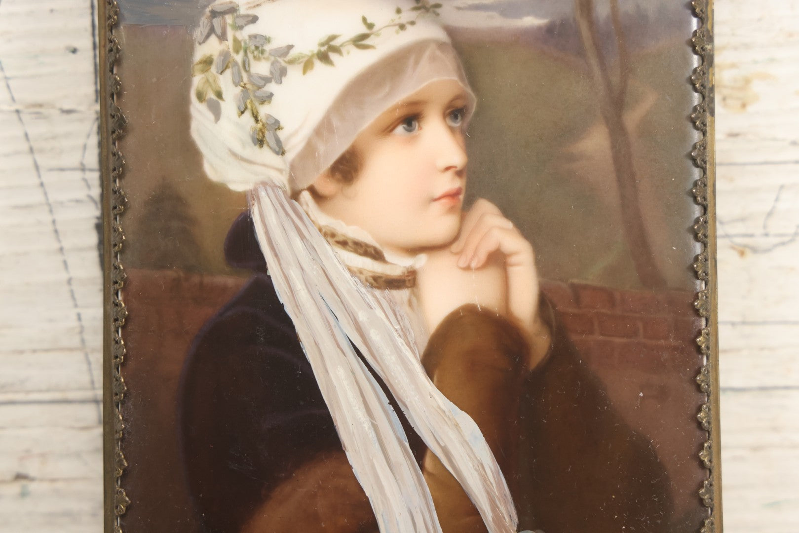 Lot 012 - Antique Painted Porcelain Tile Of Young Praying Woman In Brass Frame With Crest, Note Large Diagonal Crack Through Tile And Multiple Cracks From Upper Left Corner Damage, 4-7/8" x 9-1/8"