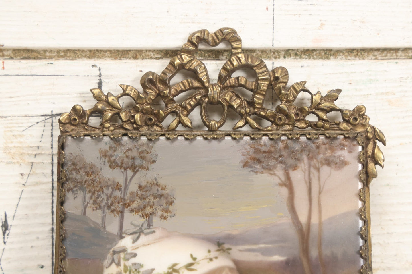 Lot 012 - Antique Painted Porcelain Tile Of Young Praying Woman In Brass Frame With Crest, Note Large Diagonal Crack Through Tile And Multiple Cracks From Upper Left Corner Damage, 4-7/8" x 9-1/8"