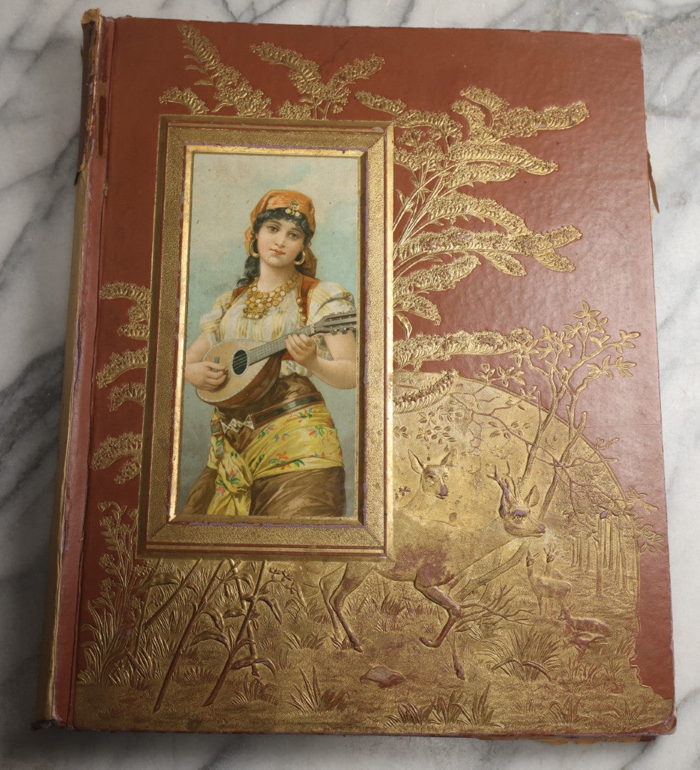 Lot 078 - Antique Scrapbook Album With Gold Embossed Deer In Forest And Pasted Gypsy Woman Chromolithograph On Cover, 150+ Victorian Trade Cards, Die Cuts, Children, Pets And Women's Fashion, Circa 1898