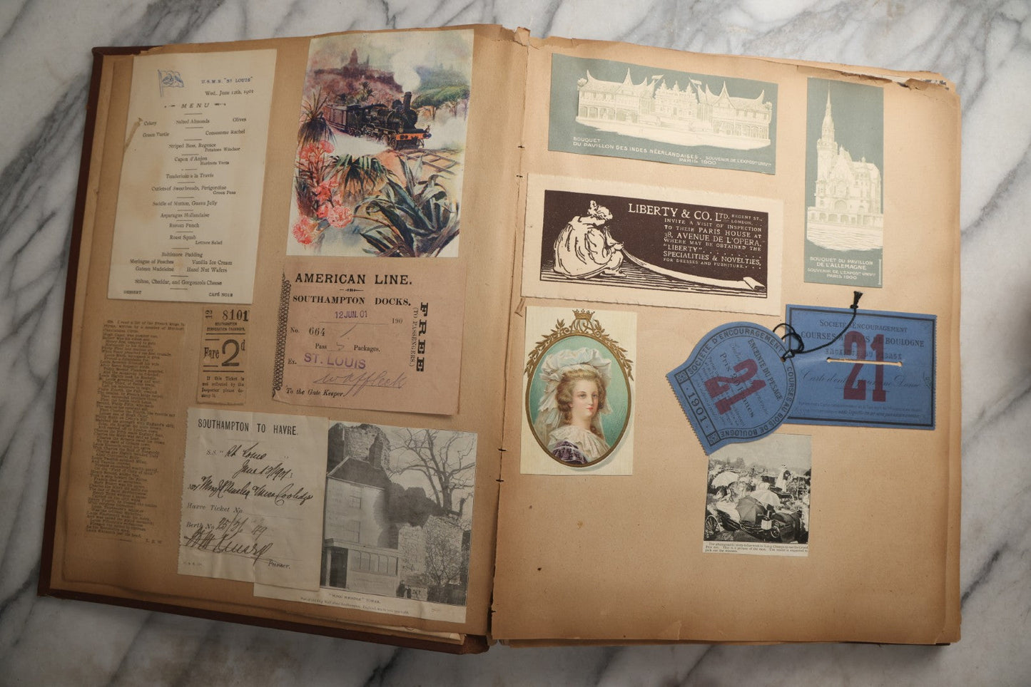 Lot 082 - Antique Brown Scrapbook Album With Gold Borders, European Travel Ephemera Including Touraine, Northern Spain, Holland, Wales, Thomas Cook Tickets, Hotel Menus, Postcards, Pressed Flowers, Circa 1901