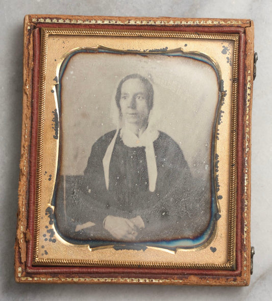 Lot 099 - Antique 1/6th Plate Daguerreotype Photograph Of Worried-Looking Middle-Aged Woman In White Bonnet With Long Ties, Hands Folded In Lap, In Half Leatherette Union Case