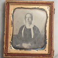 Lot 099 - Antique 1/6th Plate Daguerreotype Photograph Of Worried-Looking Middle-Aged Woman In White Bonnet With Long Ties, Hands Folded In Lap, In Half Leatherette Union Case