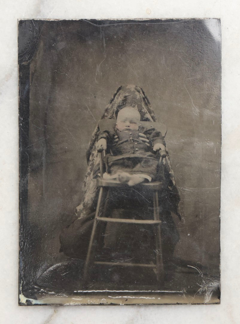 Lot 104 - Antique Hidden Mother Tintype Photograph Of Baby In High Chair With Mother Or Assistant Conspicuously Concealed Beneath Floral Blanket Behind Chair