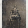 Lot 104 - Antique Hidden Mother Tintype Photograph Of Baby In High Chair With Mother Or Assistant Conspicuously Concealed Beneath Floral Blanket Behind Chair