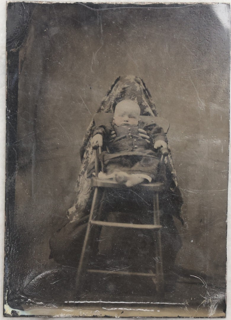 Lot 104 - Antique Hidden Mother Tintype Photograph Of Baby In High Chair With Mother Or Assistant Conspicuously Concealed Beneath Floral Blanket Behind Chair