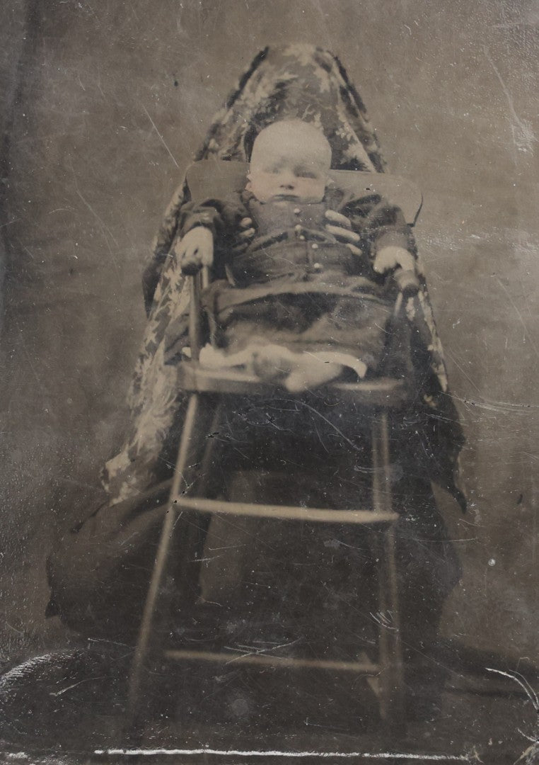 Lot 104 - Antique Hidden Mother Tintype Photograph Of Baby In High Chair With Mother Or Assistant Conspicuously Concealed Beneath Floral Blanket Behind Chair