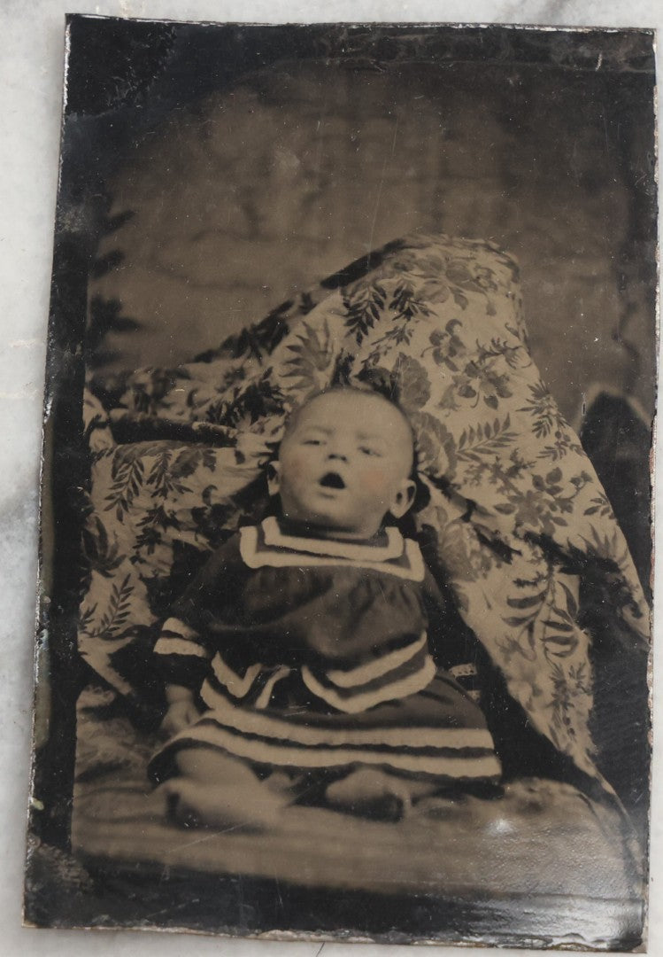 Lot 105 - Antique Hidden Mother Tintype Photograph Of Baby With Mouth Agape, Seated With Mother Or Assistant Conspicuously Concealed Beneath Floral Blanket Behind Baby