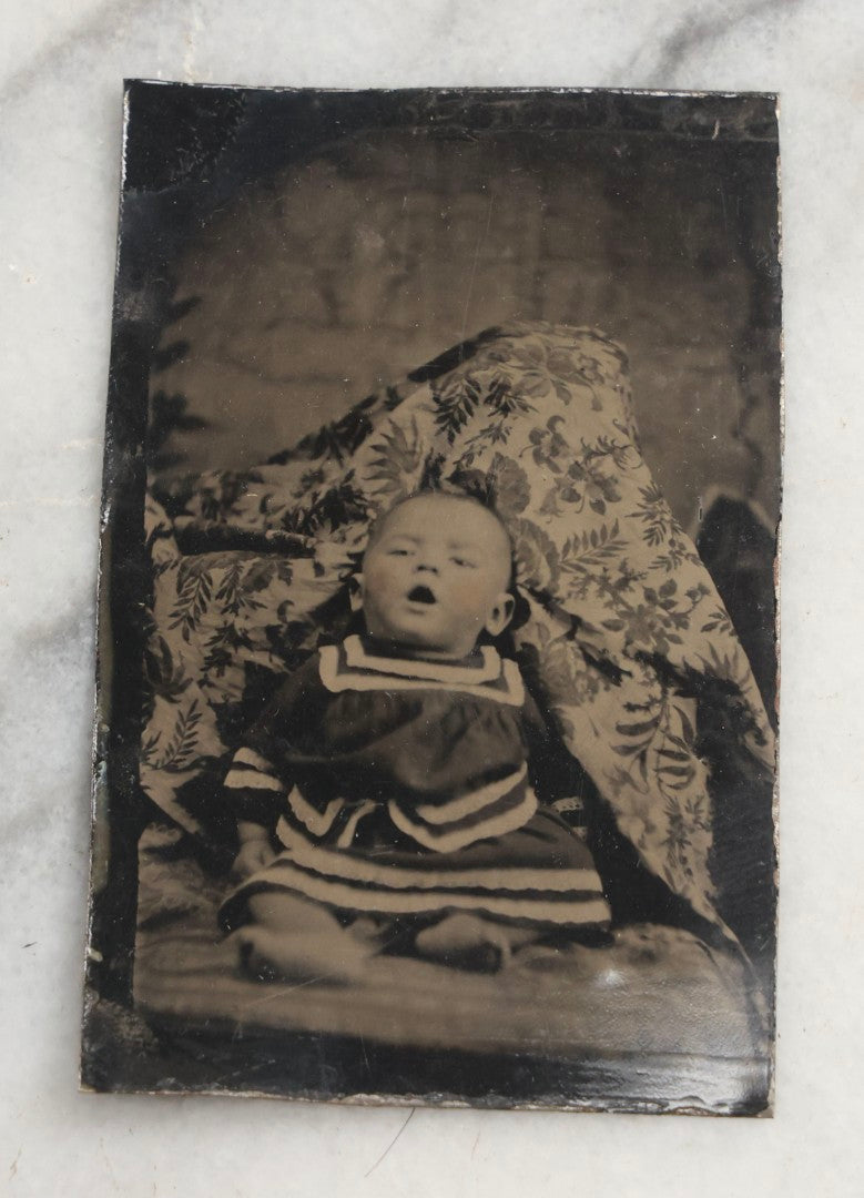 Lot 105 - Antique Hidden Mother Tintype Photograph Of Baby With Mouth Agape, Seated With Mother Or Assistant Conspicuously Concealed Beneath Floral Blanket Behind Baby
