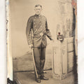 Lot 108 - Antique Tintype Photograph Of Uniformed Militiaman In Double-Breasted Coat With Shoulder Scales And Sword, Kepi On Pedestal, In Studio Setting
