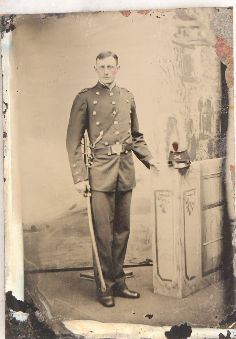 Lot 108 - Antique Tintype Photograph Of Uniformed Militiaman In Double-Breasted Coat With Shoulder Scales And Sword, Kepi On Pedestal, In Studio Setting