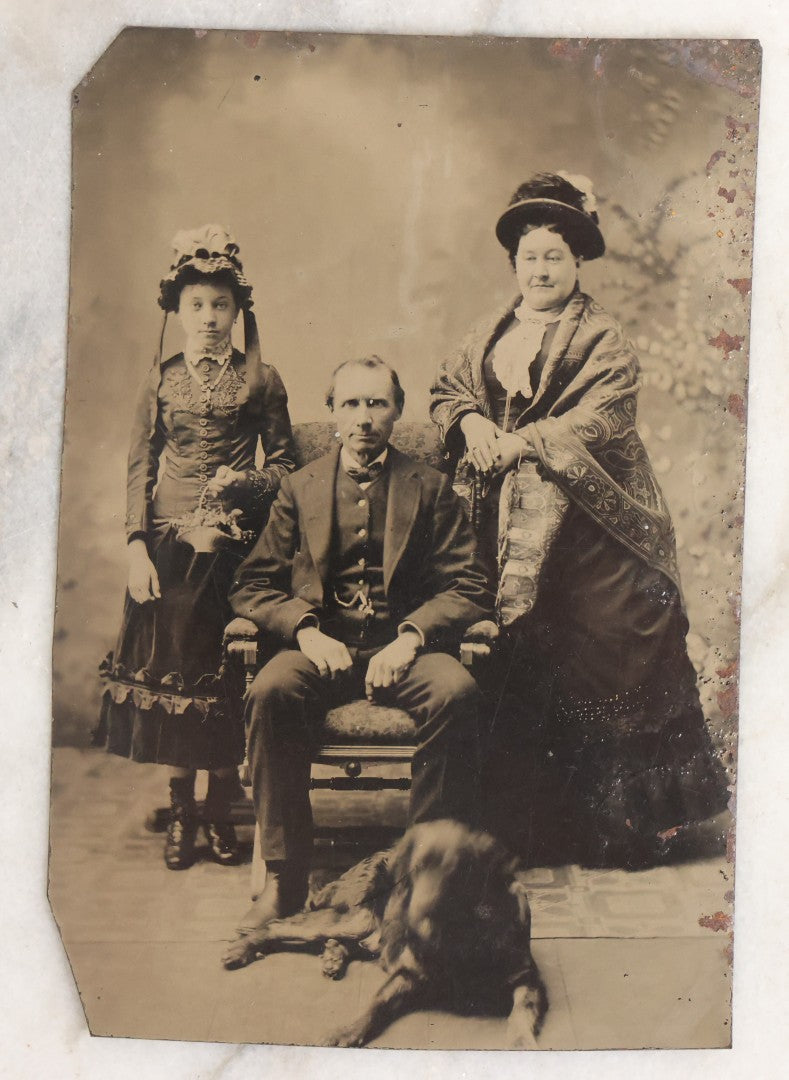 Lot 110 - Antique Near Half Plate Tintype Photograph Of Family Group With Mother, Father, Daughter, And Blurry Black Dog Seated At Their Feet, In Black Paper Frame
