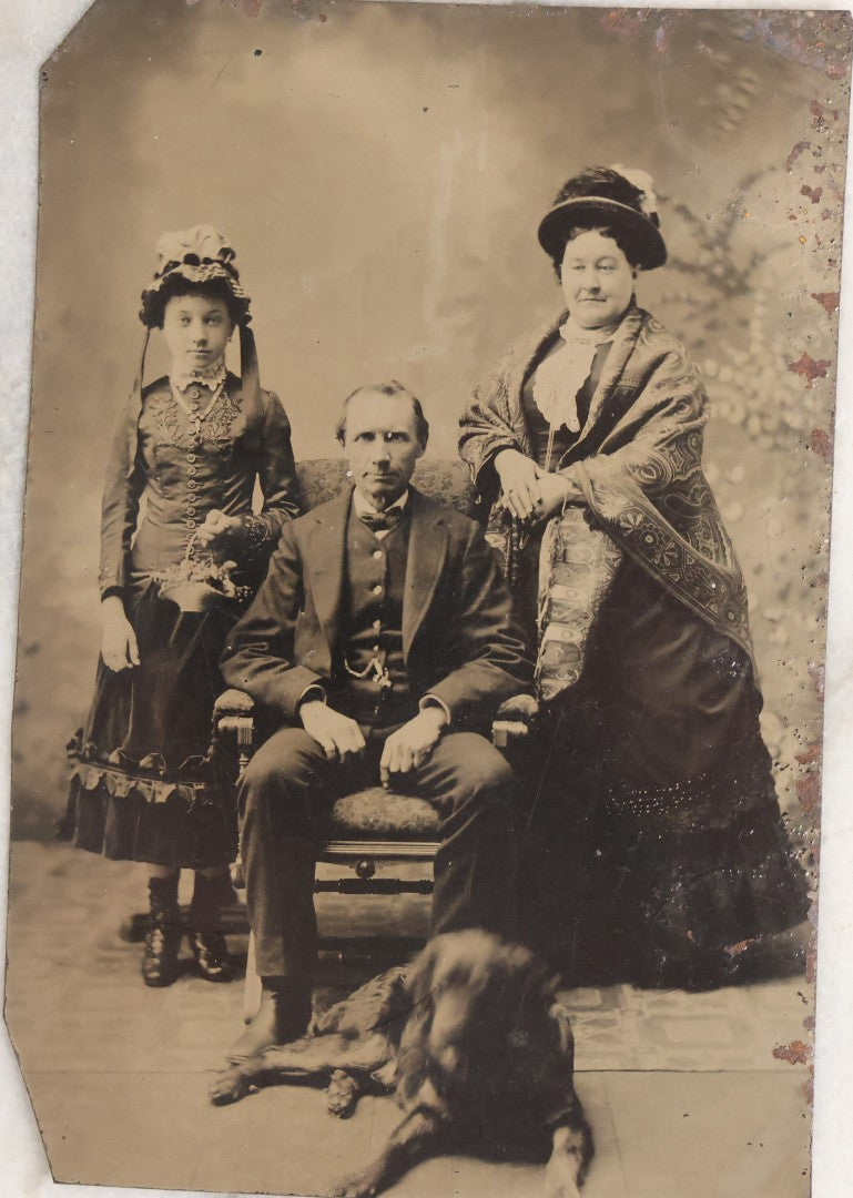 Lot 110 - Antique Near Half Plate Tintype Photograph Of Family Group With Mother, Father, Daughter, And Blurry Black Dog Seated At Their Feet, In Black Paper Frame