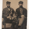 Lot 111 - Antique Tintype Photograph Of Two Bearded Men In Caps With Rambunctious Spotted Dog Seated On Lap, Dog Blurred From Motion
