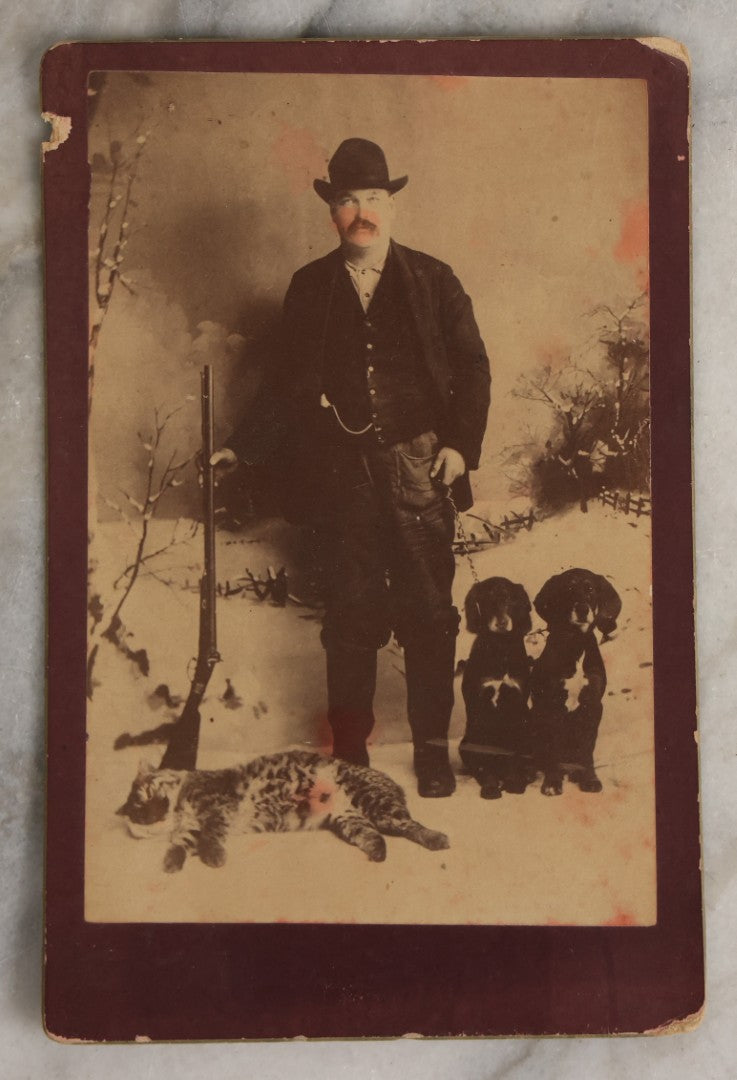 Lot 114 - Antique Cabinet Card Photograph Of Hunter With Rifle, Two Puppies, And Dead Wildcat In Snowy Outdoor Backdrop