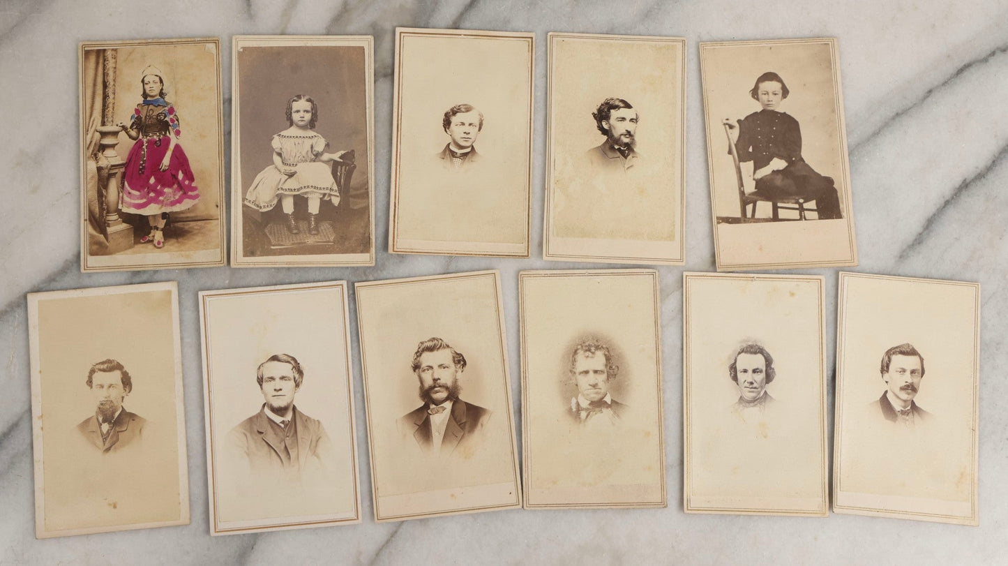 Lot 127 - Grouping Of Eleven Antique Carte De Visite C.D.V.. Photographs Including Hand-Colored Portrait Of Young Girl In Traditional Dress, Boy In Chair, Girl In Dress, And Multiple Men's Portraits
