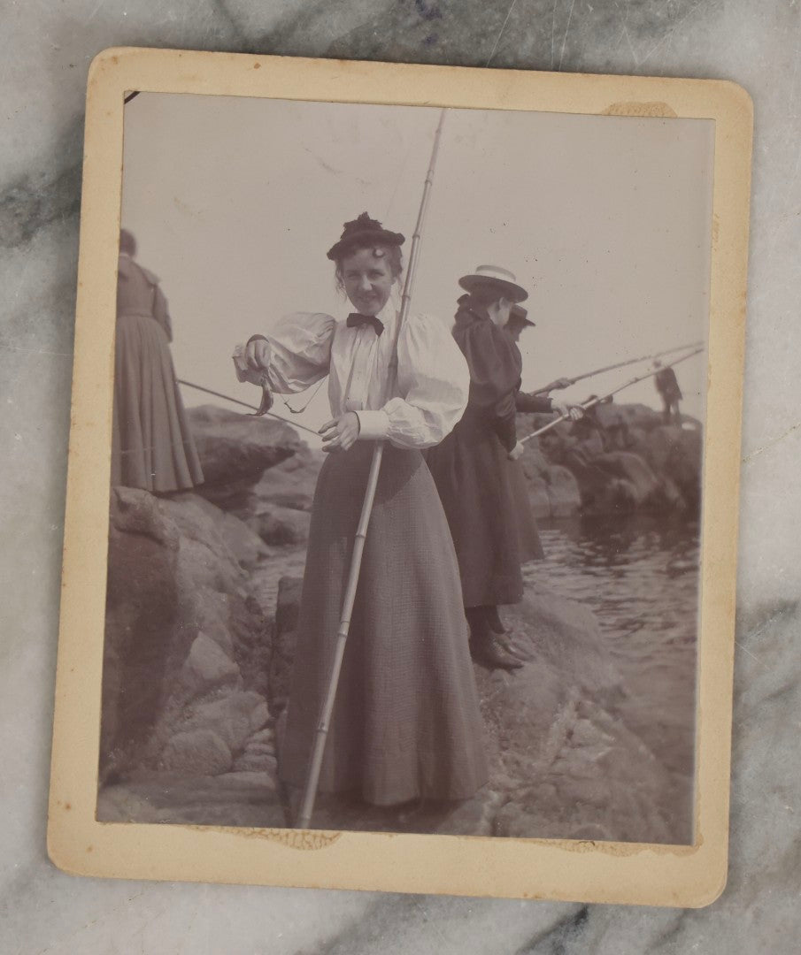 Lot 128 - Grouping Of Five Antique Outdoor Boarded Photographs, Victorian Era, Including Woman Fishing July 1896; Three Women Seated On Rocky Shore; Large Group With Dog June 1896; Ladies Posed On Porch Of “Chase Cabin”; And Group With Dog