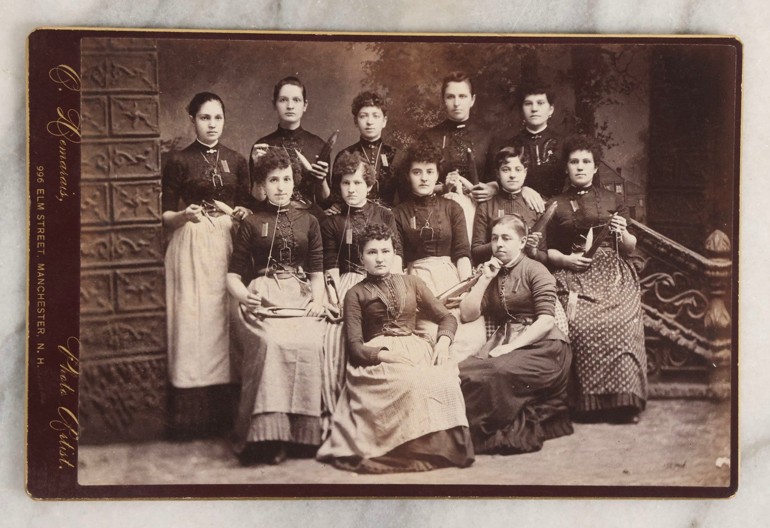 Lot 133 - Antique Cabinet Card Photograph Of Twelve Women Posed With Sewing Tools And Apparatus, Including Thread, Bobbins, And Scissors, Photographed By O. Desmarais, 999 Elm Street, Manchester, New Hampshire