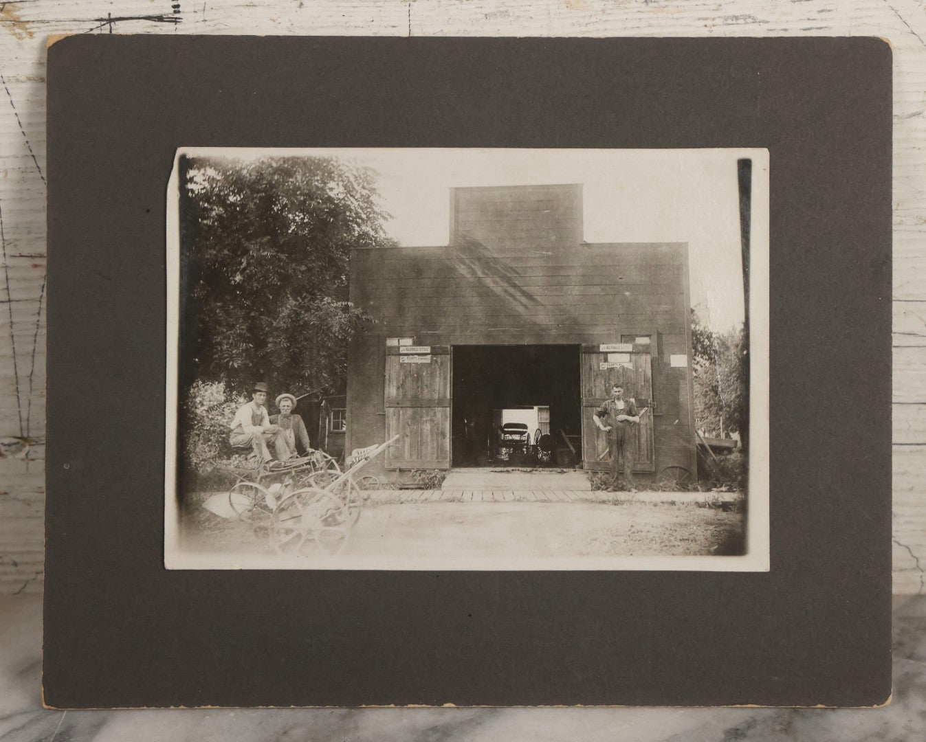 Lot 141 - Antique Boarded Photograph Of Garage With Early Automobile, Kendall's Spavin And Flint's Powder Signage, Three People With Wagon