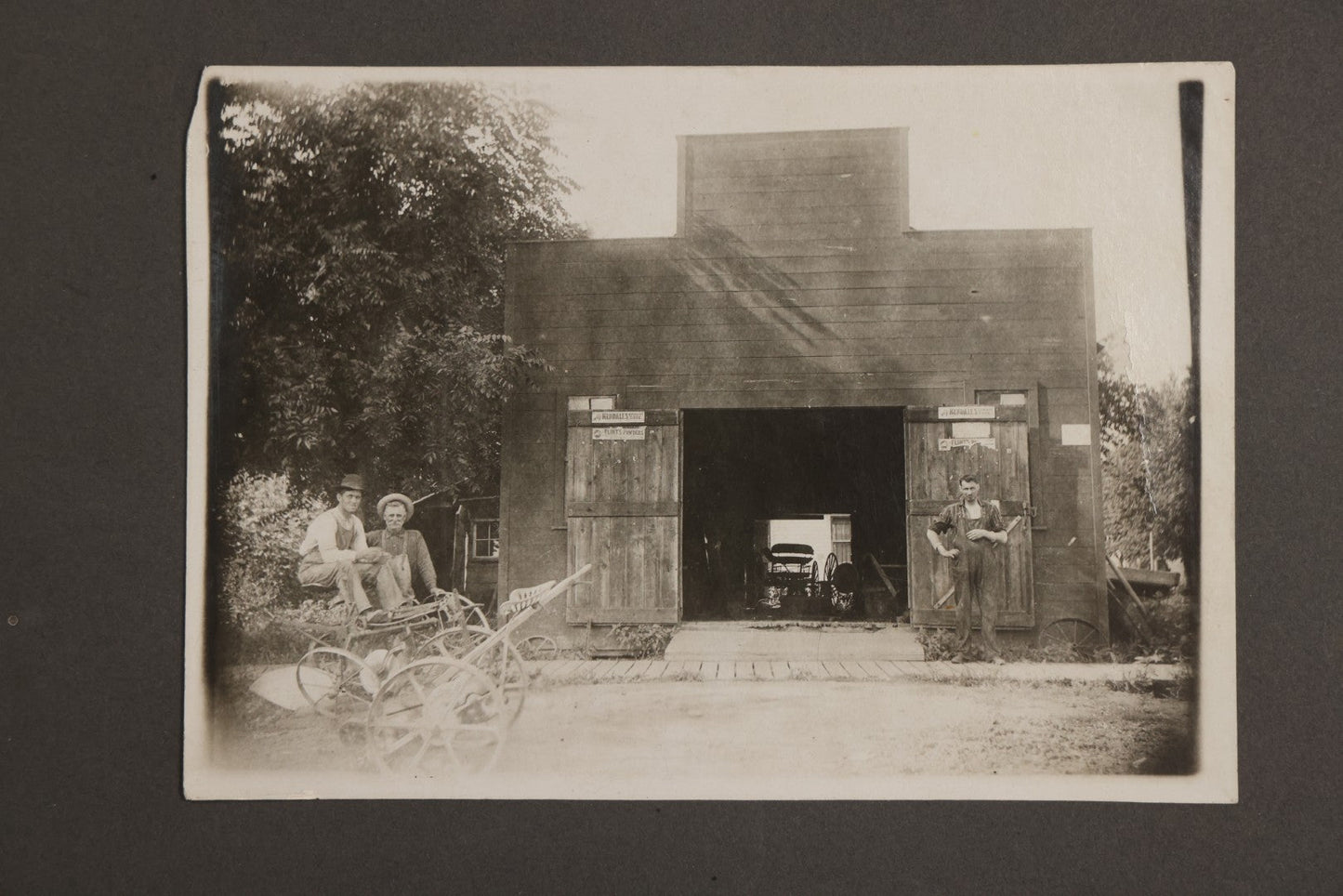 Lot 141 - Antique Boarded Photograph Of Garage With Early Automobile, Kendall's Spavin And Flint's Powder Signage, Three People With Wagon