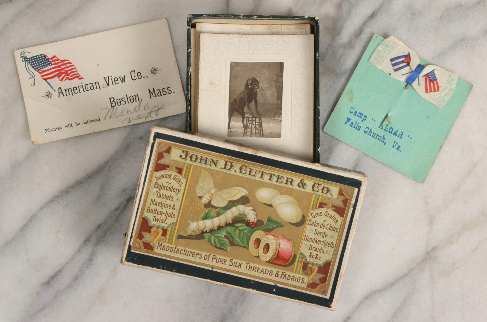 Lot 151 - Antique Box Lot Of Fifteen “Pocket Kodak” Miniature Boarded Photographs Including Dog On Stool, Boys Smoking Pipes, And Man In Workshop, With Camp Alger Flag Pin And American Views Co. Trade Card In John D. Cutter & Co. Chromolithograph Box