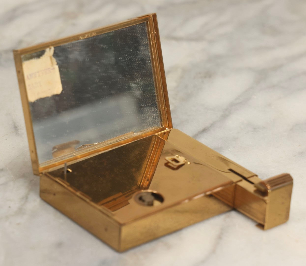 Lot 059 - Vintage Volupte Brass Makeup Compact With Pull-Out Lipstick Holder And Wind Up Musical Box, Made In U.S.A..
