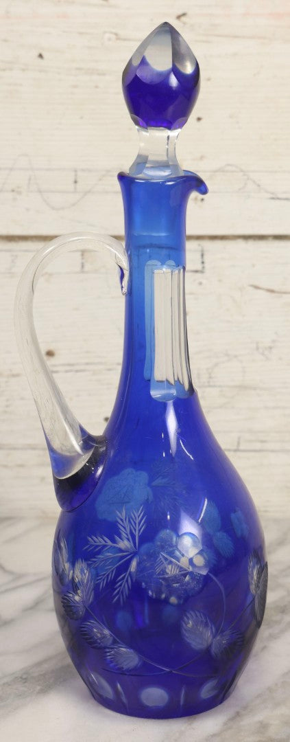 Lot 063 - Vintage Cobalt Blue Cut-To-Clear Glass Decanter With Floral Decoration, Applied Handle, And Faceted Stopper